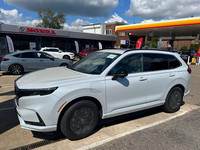 A 2024 Honda CR-V in Platinum White Pearl drives off the transporter